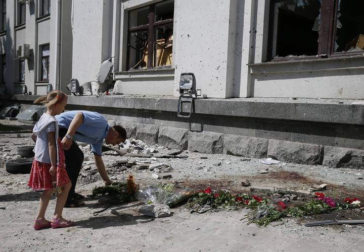 A man places flowers near the site of an explosion in a regional administration building in Luhansk